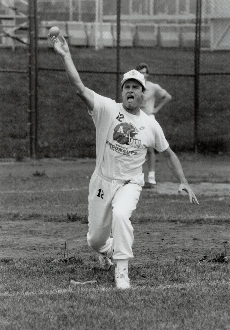 Argo quarterback Mike Kerrigan pitches during a pre-practice baseball game yesterday