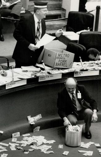 Money scramble: North York Controller Bob Yuill tosses around $1 bills during Metro Council budget debate yesterday to protest Metro's tax increase