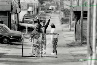 Back lane breakaway. Above, Brendan Clarke, 17, Jamie Robak, 18, as he breaks in on goal yesterday while playing ball hockey in an alley in the Hanson(...)