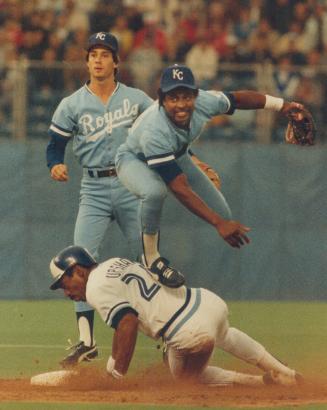 Right, Frank WHite of Royals leaps over Willie Upshaw at second, but was late with throw to first [Incomplete]