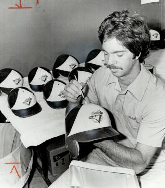 Artist at work: Blue Jays' clubhouse attendant Jeff Ross applies the finishing touches to the Jays' batting helmets prior to today's opening of spring training in Dunedin, Fla