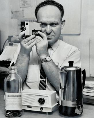 In the picture: Manager Jack Kalb of Plaza Bowling Alleys checks a new movie camera he's raffling off along with a radio and coffee pot for Sportmen's Corner