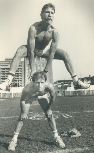 Asutralians Peter Carey (top) and Bryan Sheehan limber up for their task Sunday of umpiring an Australian Rules football game at Varsity Stadium. It'l(...)