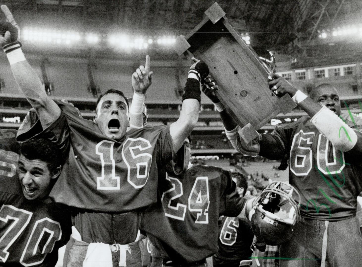 Happy gang: Laurier Hawks celebrate with the Churchill Bowl trophy after their 42-22 comeback win over Queen's Golden Gaels at the SkyDome yesterday