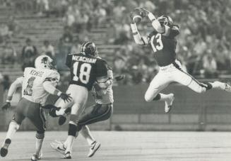 Argos' defensive back Darrell Wilson leaps to intercept Roy Dewalt pass intended for John Pankratz (behind Lamont Meacham.)