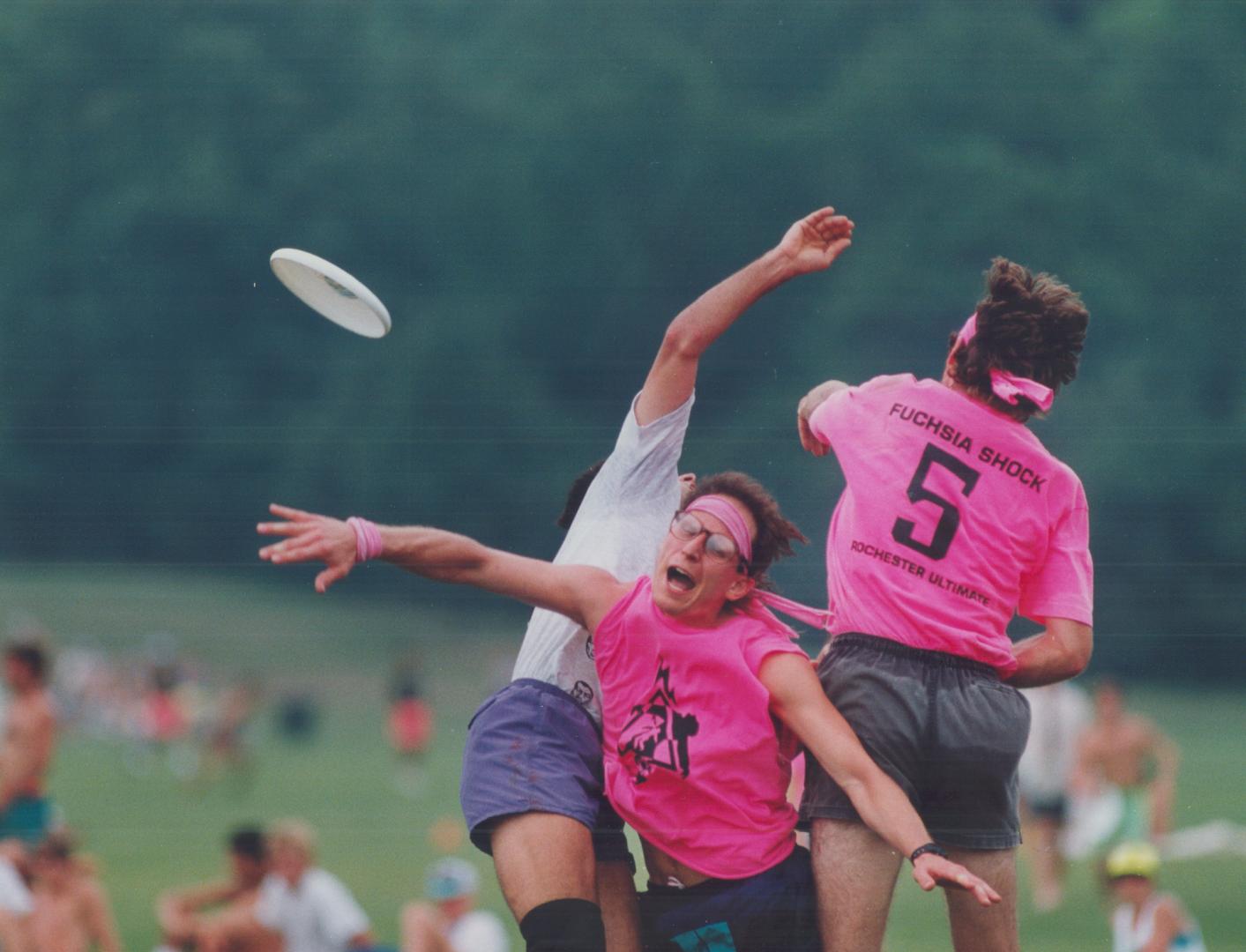 Playing the ultimate way. Dave Northrup, right, of Rochester's Fuschia Shock squad, jumps into a Frisbee tray with a teammate, centre, and an opponent(...)