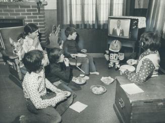 This informal family gathering in front of the TV set is typical of the scenes which will take place in many homes across Canada on Sunday while the b(...)