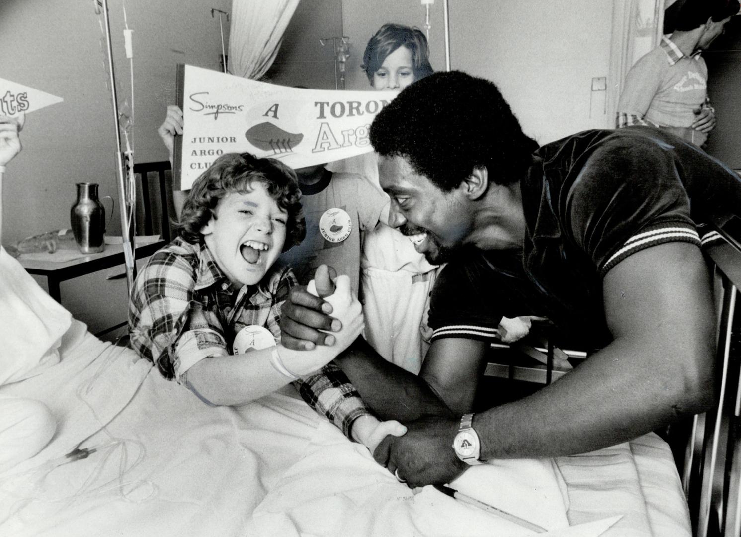 Therapeutic twist. Doug Hinks, 11, of Rexdale go to tackle Argo defensive back Billy Hardee in an arm wrestling match yesterday. The ARgonauts were vi(...)