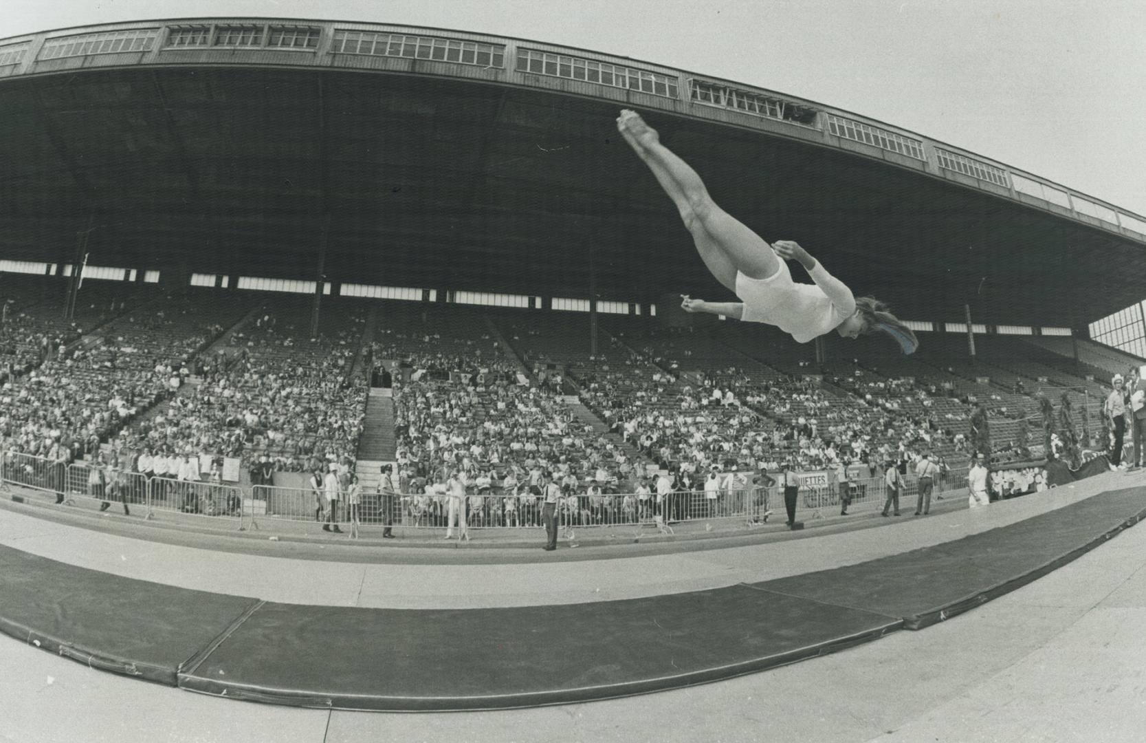 Twisting High in the air in a flying somersault, 16-year-old gymnast Jennifer Diachun, Canadian senior champion, performs for a crowd of about 7,000 a(...)