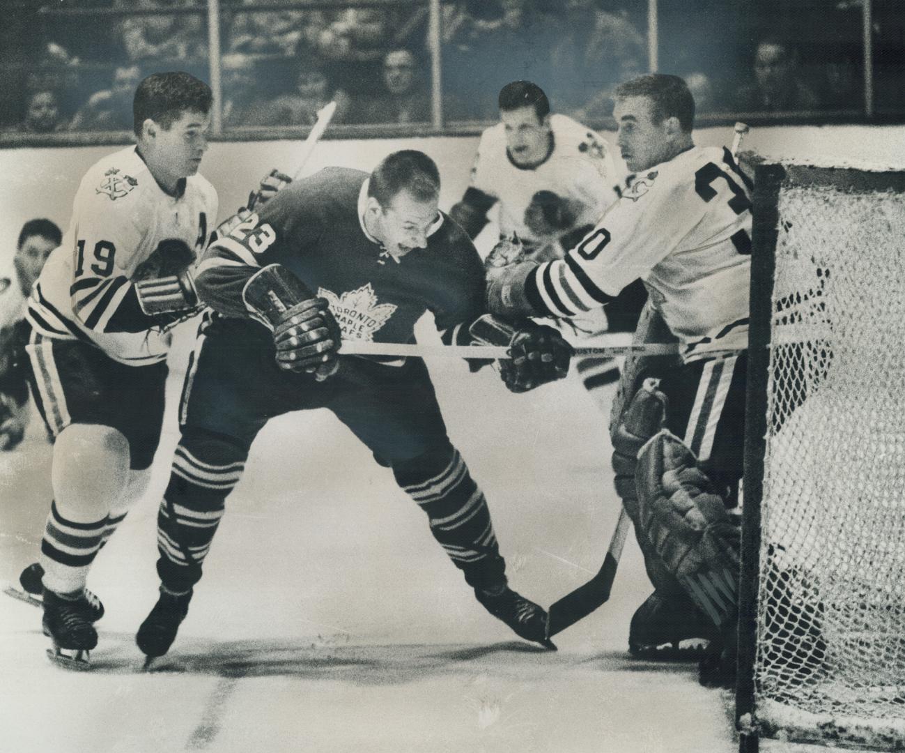 Leafs' Eddie Shack (23) wreaks Havoc in black hawks' goalmouth Chicago's Al MacNeil (19) and netminder Denis Dejordy (30) fend him off