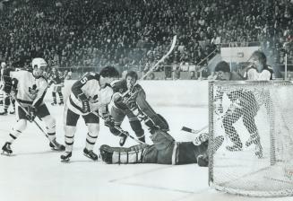 Digging Away: Leafs' Pat Boutette (15) digs the puck out from under sprawling New York goalie Dunc Wilson during Saturday night's NHL game at Maple Leaf Gardens