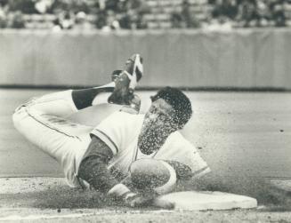 John Mayberry raises a cloud of dust as he slides into third base during the Blue Jays' five-run second inning