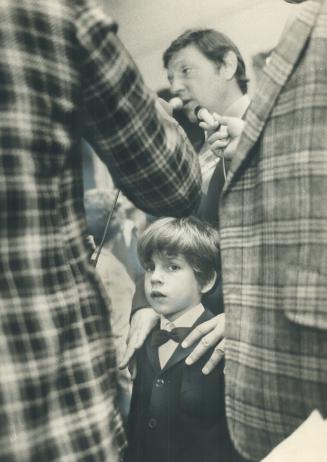 While his son, Michael, 7, looks on in amazement, Roy McMurtry, 43, the province's new attorney-general, talks to reporters today at Queen's Park afte(...)