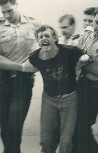 Frederick Merrill screams as police escort the fugitive in Peel headquarters yesterday