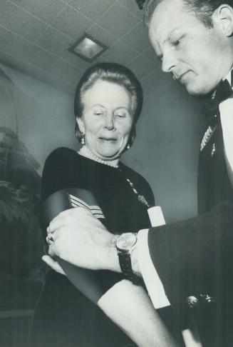 Mrs. Roland Michener, wife of the Governor-General, is presented with her sergeant's stripes by Regimental Sergeant-Major Hans Busch at a dinner in he(...)