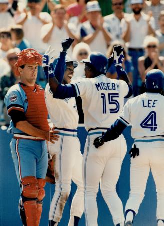 Welcome home: Tony Fernandez led the welcome party when Moseby arried at home plate after his grand slam homer had tied the game and erased the Twins' 4-0 lead