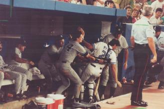 Blue Jays catcher Greg Myers is saved from a crash landing in the New York Yankees dugout