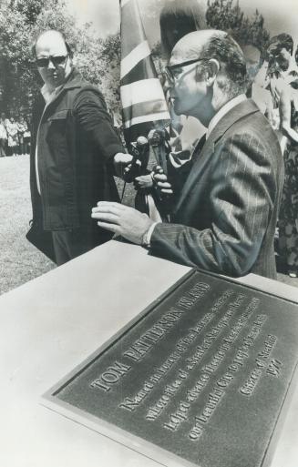 Festival founder Tom Patterson stands beside commemorative plaque on island named after him