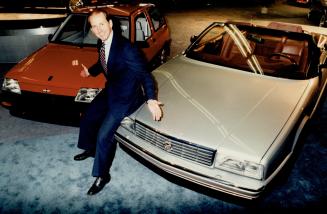 Sitting pretty, GM Canada chief George Peapples shows off GM's priciest Cadillac at the right and one of its cheapest cars