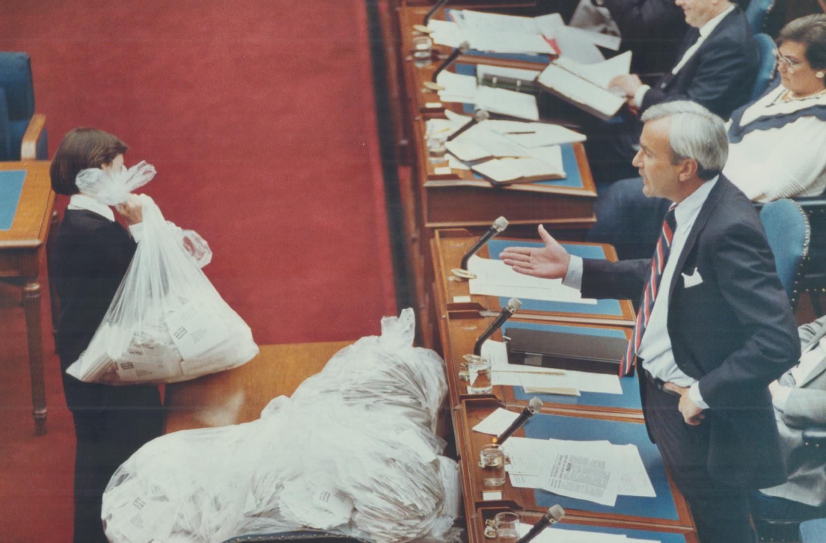 He gets mail, Premier David Peterson watches as a Legislature page brings one of 15 bags of protest postcards in the House yesterday. The postcards ar(...)