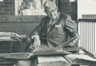 Former Mayor Nathan Phillips looks over his city hall scrap book at his home