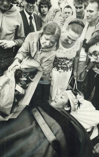 While her mother (centre) looks on, a friend presents roses to a smiling Elizabeth