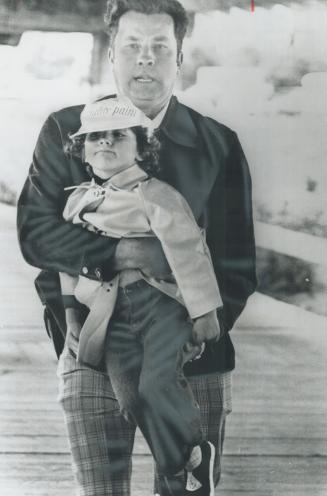 Harassed babysitter: An RCMP plainclothes man carries 4-year-old Justin back to his mother, Margaret Trudeau, before Prime Minister arrived at Habitat