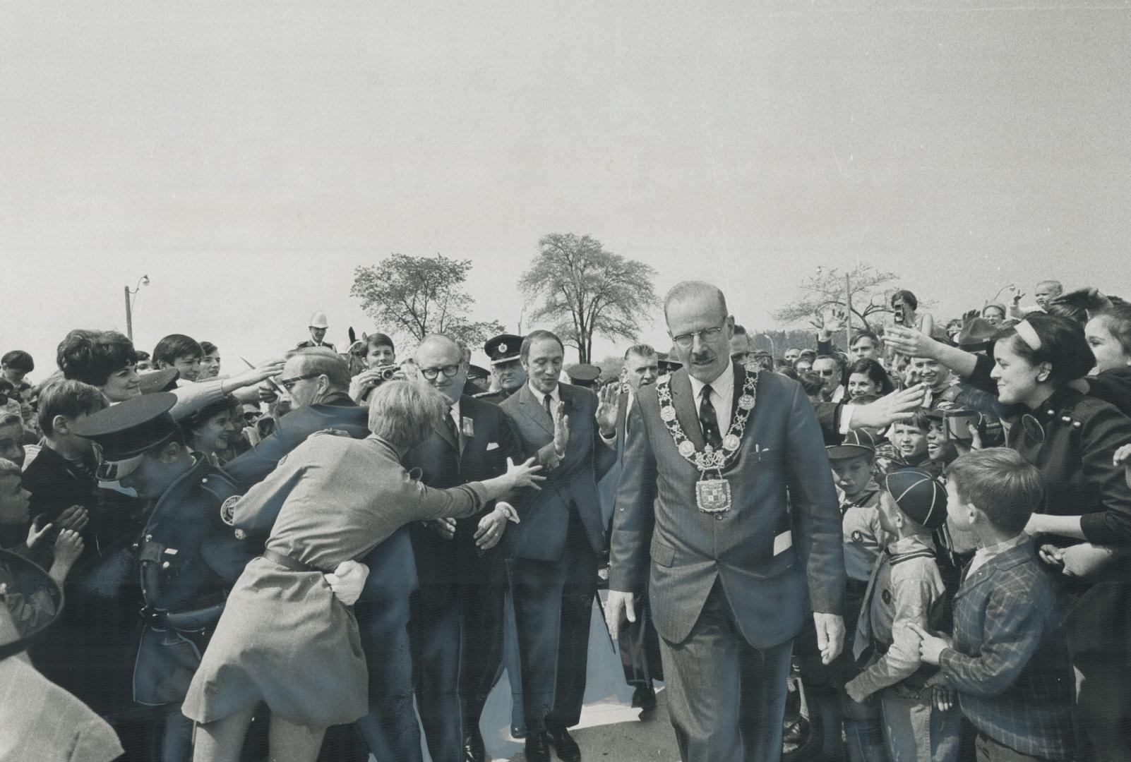 It's a No! No! Prime Minister Pierre Trudeau's gesture indicates as he motions disclaimingly to eager fans reaching out to clutch at him during offici(...)