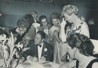 Putting it in writing: Prime Minister Pierre Elliott Truedeau is surrounded by autograph seekers at last night's Toronto and District Liberal Association dinner-dance at the Royal York Hotel