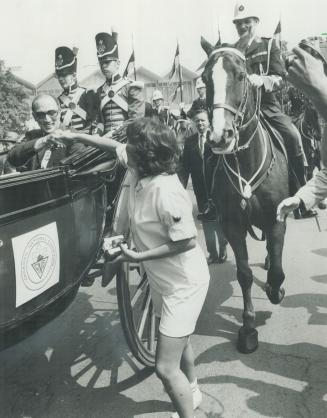 A regal ride: A woman shakes the hand of Prime Minister Trudeau ah he rides a landau to the formal opening of the Canadian National Exhibiton yesterday