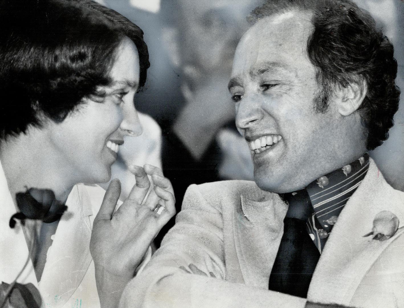 Holding a rose, Margaret Trudeau smiles at her husband, the Prime Minister, after his speech last night in Varsity Stadium. He asked Toronto to vote for a strong team