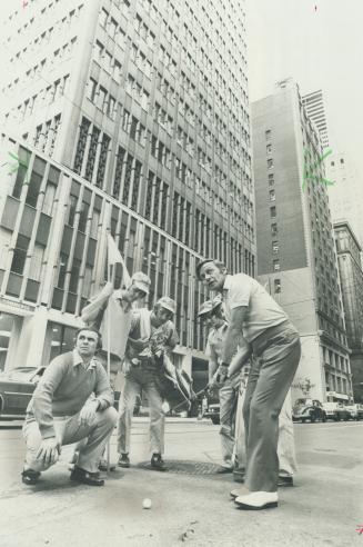 Watched by caddies, comics John Wayne (left) and Frank Shuster (right) tee off from piece of plasticine on King St