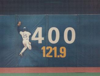 Toronto Blue Jays player jumping to catch ball into barrier with the numbers 400 and 121 point …