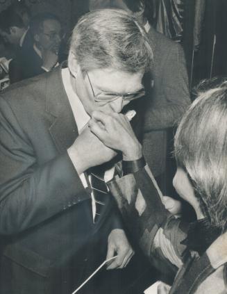 Chivalry's alive: Finance Minister Michael Wilson kisses the hand of an admirer during a session of autographing copies of his new budget at a breakfast meeting in his home riding yesterday