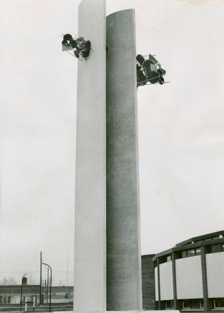 Two tall, parallel, concrete slabs with clusters of metal discs and spokes affixed to upper, ou…