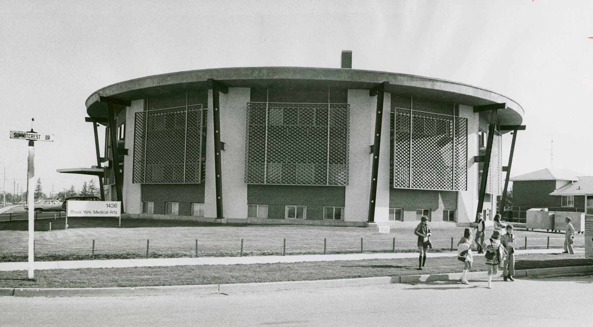 Octagonal, disc shaped, three-storey flat-roofed building with large mesh panels covering secon ...