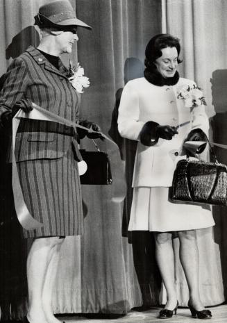 Mrs. John Robarts, wife of the premier of Ontario, cuts the ribbon to offcially open the Women's World five-day exhibition at the Queen Elizabeth Buil(...)