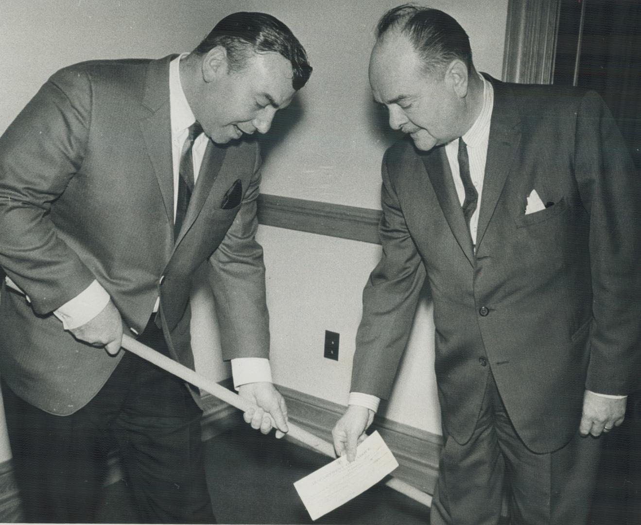 Here's puck that won't bounce. Labor Minister Leslie Rowntree of Ontario (right) finds a new way to present cheque for $750 to Canadian Italian Hockey(...)