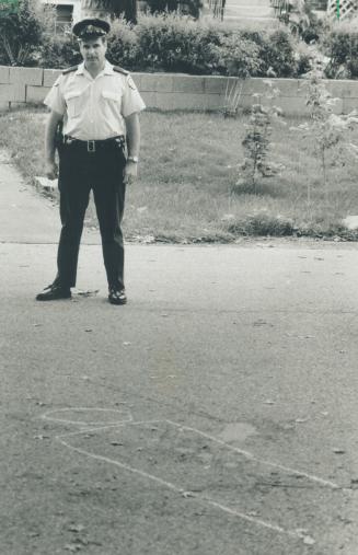 Shooting scene: An officer stands guard over the spot where Dominic Sabatino was shot by police following a tense confrontation yesterday in Etobicoke