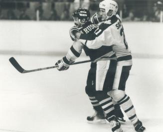 All wrapped up: Terry Ruskowski of the Pittsburgh Penguins is trying hard to get to the puck, but defenceman Borje Salming of the Leafs has him all tied up in a bear hug at the Gardens last night