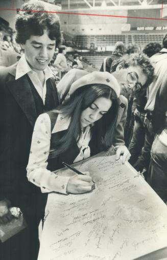 Maple Leaf Gardens usherette Maria DiSalle signs a 20-foot-long (6 metre) get-well card for Leafs' injured star defeceman Borje Salming. Canadian Hebr(...)