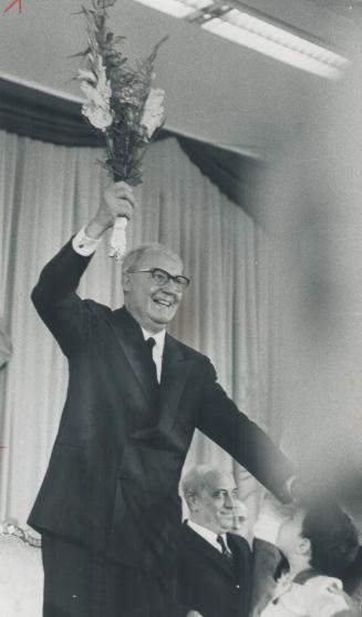 President Saragat of Italy holds aloft the bouquet he received from a 7-year-old Italian-Canadian boy after his arrival last night at the Queen Elizab(...)