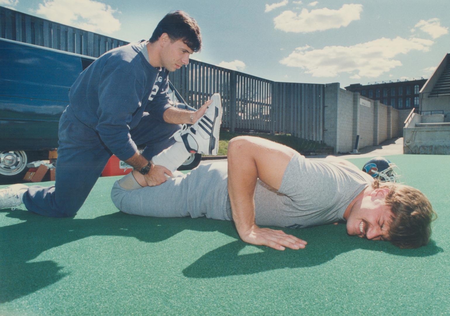 Argos offensive lineman Chris Schultz loosens up with the help of assistant trainer John Gransaull prior to yesterday's practice at Lamport Stadium. W(...)