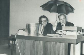 Some aldermen are all wet. Holding an umbrella, Alderman Reid Scott sits next to Alderman David Smith--and a bucket to catch the water leaking through(...)