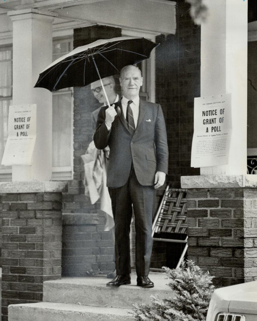 Umbrella held high, External Affairs Minister Mitchell Sharp paid a visit to a polling station on Chatsworth Dr. soon after it opened this morning. Th(...)