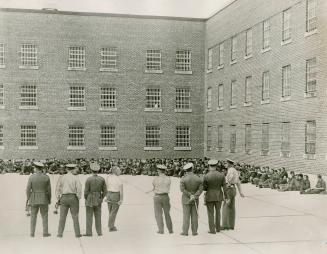 Guelph Reformatory guards watch over inmates herded into the exercise quadrangle