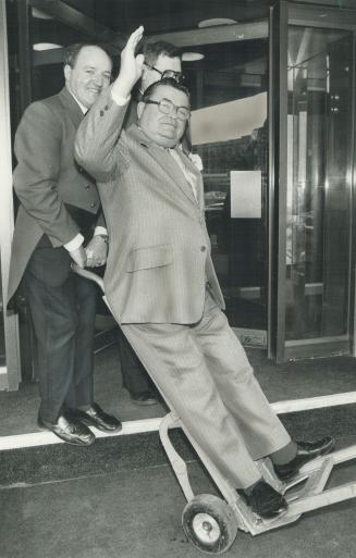 Bellman puts his feet up: Bill Bilecki, bellman at Royal York hotel for 45 years, is wheeled out of the hotel by bell captain Gerry Lockman after a send-off from friends and co-workers.