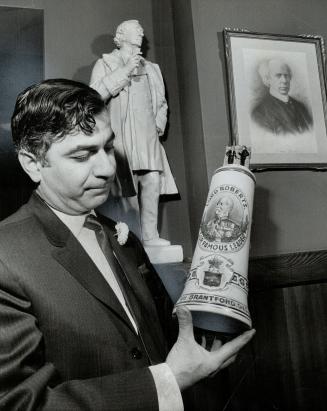 Harry Barberian holds old beer stein made in Brantford, The restaurateur is also a collector of Canadian paintings, books and other treasures.