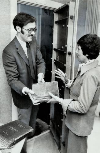 Director of the Bureau of Municipal Research, Charles Bens, handing files to researcher Anne Golden, says it has a good batting average.