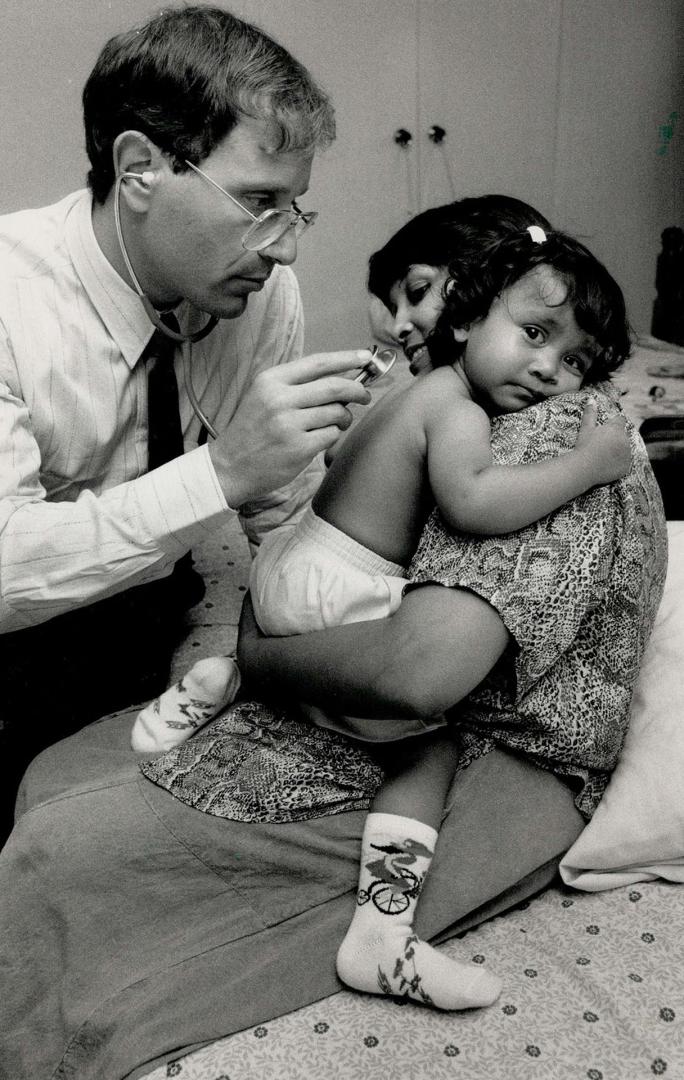 Home visit: Amanda Persad, 18 months, keeps a firm grip on mother Anna while being checked out by Dr. Tom Berko, who has recently started a housecall service in Scarborough.